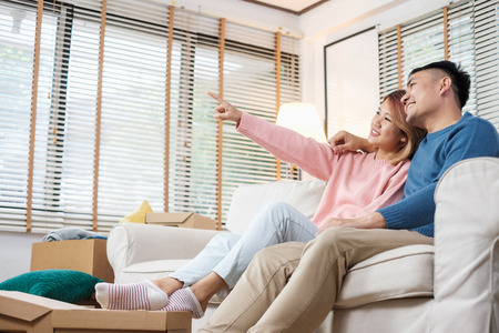 Asian couple planning to decorate house after moving to new home,sitting on sofa with relax emotionの写真素材