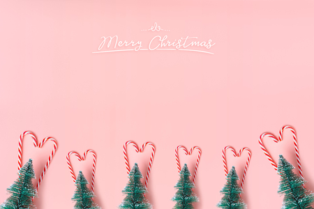 Tree Christmas tree with candy cane hanging on pastel pink wall with white Merry christmas word.Holiday festive celebration greeting cardの写真素材