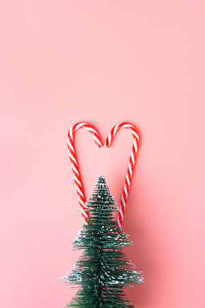 Christmas tree with candy cane hanging on pastel pink wall.Holiday festive celebration greeting cardの写真素材