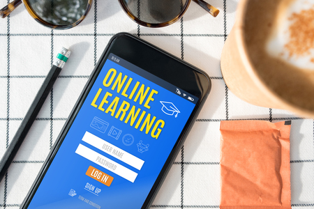 top view online learning log in  feature on mobile screen with coffee cup,sunglasses,pencil on white table cloth.digital e learningの写真素材