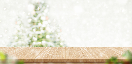 Empty brown wooden table top with abstract muted blur christmas tree and snow fall background with bokeh light,Holiday backdrop,Mock up banner for display or montage of productのイラスト素材