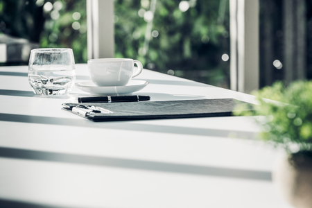 Close up business contract paper on meeting room table with pen and coffee cup in sun light shadow with green plant at office,business agreement conceptの写真素材