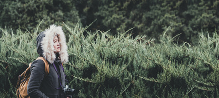 Asian woman wear coat with fur standing at green pine fir forest in winter season.copy space for...