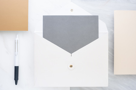Top view of blank grey card in white envelop with pine leaf on two layer step of marble table top.Mock up template for display of design.modern business itemsの写真素材