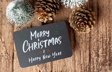 Top view of Merry Christmas and happy new year on blackboard with xmas tree and gold pine cone on grunge wood table .winter holiday greeting cardの写真素材