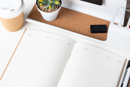 top view of open calendar planner with modern office stationery and take away coffee cup on white desk in office.mock up space of organizer table notebookの写真素材