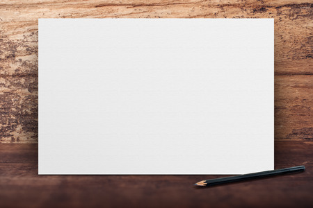 Blank banner white paper poster leaning at grunge wood wall on wooden floor in perspective room,Business mock up presentation.Template display of design or contentの写真素材