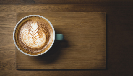 Top view of hot cappuccino coffee cup on wooden tray with latte art on wood table at cafe,food and drink dark tone,leave space for adding textの写真素材