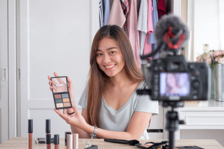 Asian young female blogger recording vlog video with makeup cosmetic at home online influencer on social media concept.live streaming viralの写真素材