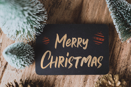 Top view of Merry Christmas and happy new year on blackboard with xmas tree and gold pine cone on grunge wood table .winter holiday greeting cardの写真素材