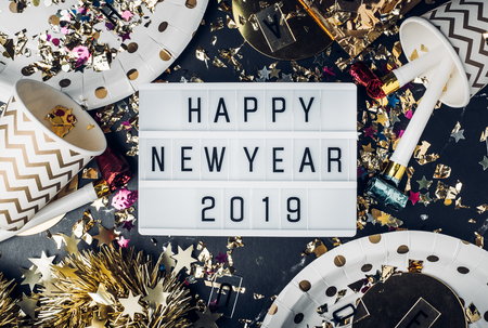 Happy new year 2019 on light box with party cup,party blower,tinsel,confetti.Fun Celebrate holiday party time table top viewの写真素材