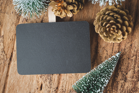 Top view of blank blackboard with xmas tree and gold pine cone on grunge wood table .winter holiday greeting card.space for display of design or contentの写真素材