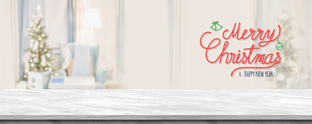 Red handwriting merry christmas and happy new year over  grey marble table top with abstract warm living room decor with christmas tree blur background with bokeh light,Holiday backdrop,Mock up bannerの写真素材