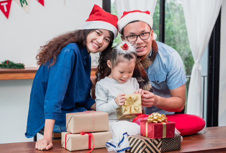 Happy family Asian family wear santa claus hat unwrap Christmas gift box at house xmas party,Holiday celebrating festive conceptの写真素材