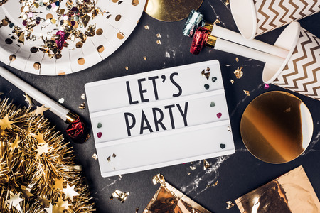Let's party on light box with party cup,party blower,tinsel,confetti.Fun Celebrate holiday party time table top view.new year and christmas conceptの写真素材