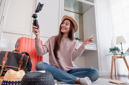 Asian young female blogger recording vlog video with mobile phone live streaming when travel.online influencer on social media viral concept