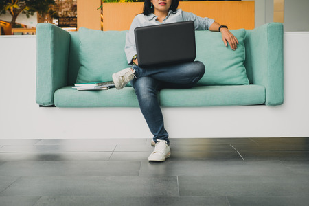 university student sitting in sofa and using laptop computer to study a lesson online,E-learning conceptの写真素材