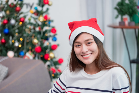 Asian woman smile at holiday party with decoration flag at background,present giving Christmas party present,winter holiday happiness momentの写真素材