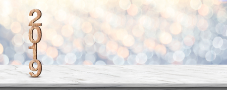 Happy new year 2019 (3d rendering wood texture) on white marble table at soft pastel blue and orange sparkle bokeh light abstract background,mock up banner space for holiday greeting cardの写真素材