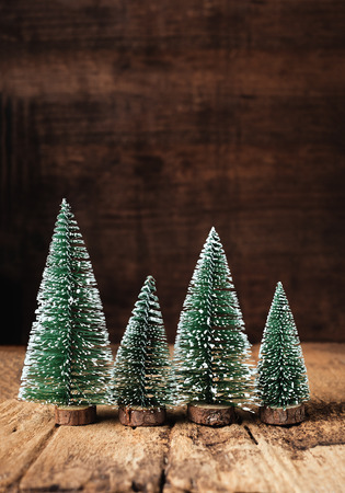 mini christmas tree wood on rustic wooden table and dark brown hardwood wall.winter holiday seasonal greeting card.leave space to adding text or designの写真素材