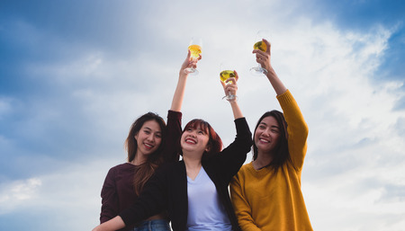 Happy group of asia girl friends enjoy laughing and cheerful toast sparkling wine glass at rooftop party,Holiday celebration festive,teeage lifestyle,freedom and funの写真素材