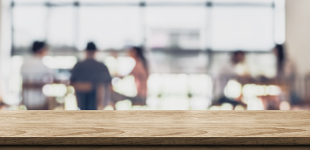 Empty wood table with blur people in coffee shop background bokeh light and leaf foreground,Mock up for display or montage of product,Banner for advertise on online media,business presentationの写真素材