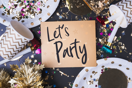 Let's party brush stroke handwriting on golden greeting card with party cup,party blower,tinsel,confetti.Holiday celebrate party time.top view tabletopの写真素材