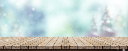 Wood table with abstract blur christmas tree and snow fall background with bokeh light.Mock up banner for display or montage of productの写真素材