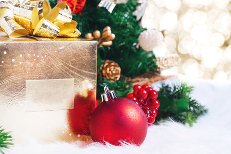 gift box and ball decoration under christmas tree on white fer with gold bokeh light background.の写真素材