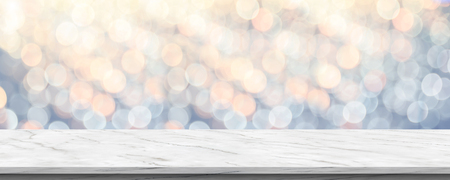 Empty white marble glossy table top with blur sparkling soft pastel blue and orange bokeh abstract background,panoramic banner for display or montage of product,Holiday seasonal concept backdropの写真素材
