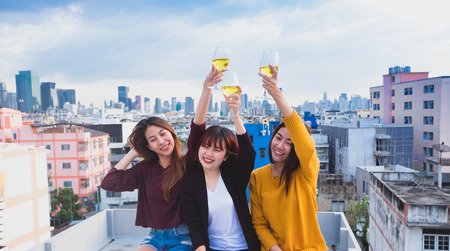 Happy group of asia girl friends enjoy laughing and cheerful toast sparkling wine glass at rooftop party,Holiday celebration festive,teenage lifestyle,freedom and funの写真素材