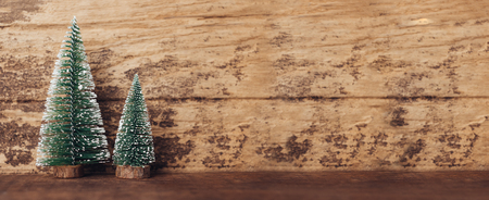 mini christmas tree wood on rustic wooden table and dark brown hardwood wall.winter holiday seasonal greeting card.banner space to adding text or designの写真素材