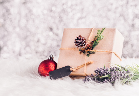 Brown paper craft warped on present box with label tag decorate with pine cone and christmas ball under xmas tree,Gift giving for holiday seasonal conceptの写真素材