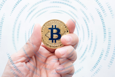 Hand holding gold bitcoin on with binary number effect on white backgorund.digital currency.banking financial technologyの写真素材