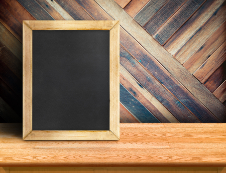 Blackboard on plank wooden table top at diagonal tropical wood wall,Template mock up for adding your design and leave space beside frame for adding more content.の写真素材
