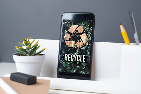 Recycle sign on green leaf on mobile app at office desk with plant and notebook.enviroment eco system conceptの写真素材