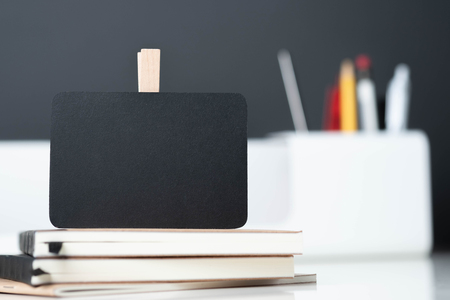 close up clip blackboard on notebook with blur modern pencil box  on table and dark grey wall in office desk,mock up space for display of design or textの写真素材