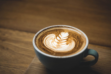 Close up hot cappuccino coffee cup with heart shape latte art on wood table at cafe,Drak tone filter,food and drinkの写真素材