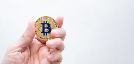 Hand holding gold bitcoin on white backgorund.digital currency.banking financial technology.banner copy space for adding textの写真素材