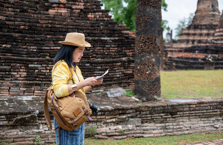 Asian tourist woman see map at ancient of pagoda temple thai architecture at Sukhothai,Thailand. Female traveler in casual thai cloths style visiting city conceptの写真素材