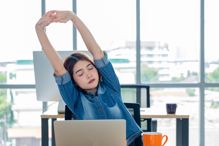 asian woman creative designer stretching arms up from working  with laptop  in modern office.take a break from workの写真素材