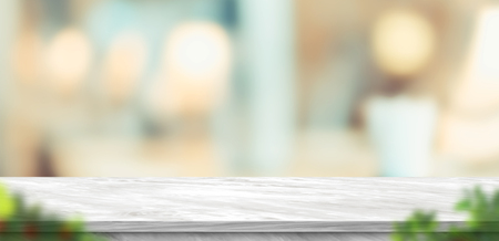 Empty grey marble table and blurred soft light table with foreground leaf in luxury restaurant with bokeh background. product display template.Business presentationの写真素材