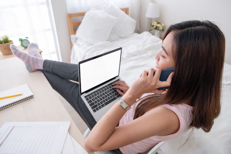top view of woman use laptop and talk on mobile with leg on table chill out working at home.mock up template device screen.Digital lifestyle concept.clipping path screenの写真素材