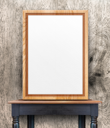 Blank wooden photo frame leaning at wood wall on vintage wood table,Template Mock up for add design or text.の写真素材