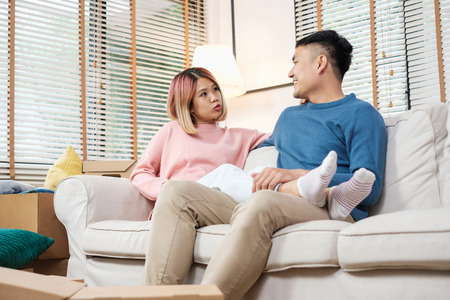 Asian couple planning to decorate house after moving to new home,sitting on sofa with relax emotionの写真素材