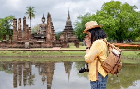 Asian tourist woman pay respect to buddha at ancient of pagoda temple thai architecture at Sukhothai,Thailand. Female traveler in casual thai cloths style visiting city conceptの写真素材