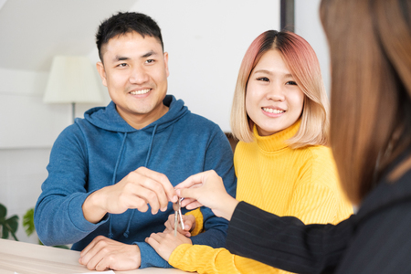 Asian happy couple getting key with realtor agent with smiling face at new home.buying new house real estateの写真素材