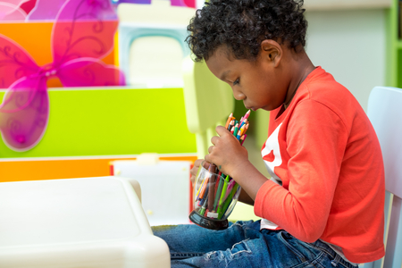Black American kid play with color pencil alone at classroom in kindergarten preschool,Education conceptの写真素材