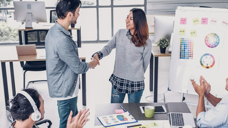 Female creative director boss handshake with designer and congratulation about getting promotion of job in modern creative officeの写真素材
