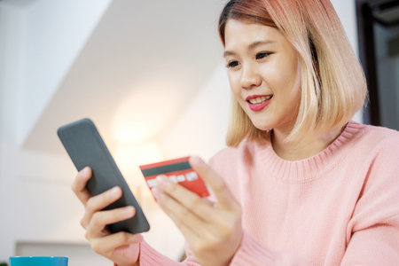 Asian woman online shopping with credit card and mobile phone at home.digital lifestyle with technologyの写真素材